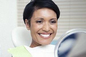 Smiling woman in dental chair looking at smile in mirror