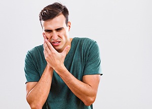 man holding his mouth in pain 