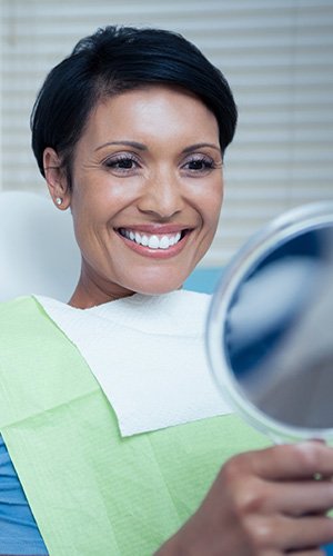 Woman in dental chair looking at smile in mirror