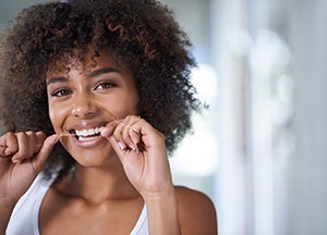 young woman smiling while flossing 