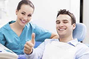 Smiling man in dental chair giving thumbs up