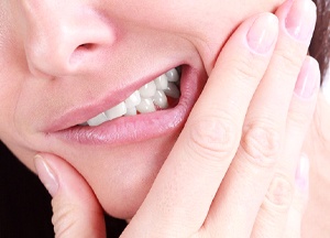 A woman holding her cheek and jaw in pain