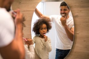 Father and daughter practice oral hygiene tips to avoid COVID-19